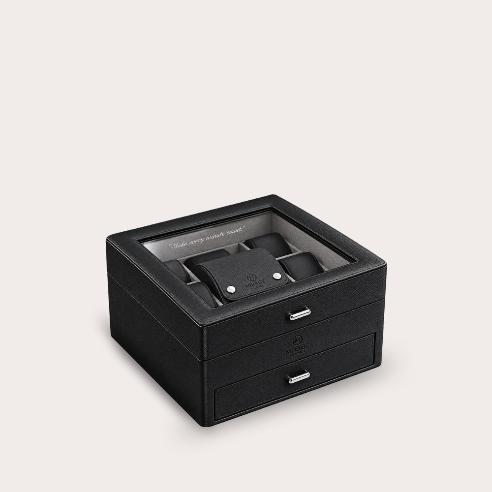 A black leather watch storage box with a transparent top lid, showing a watch inside, and two front drawers with silver handles, set against a light beige background.
