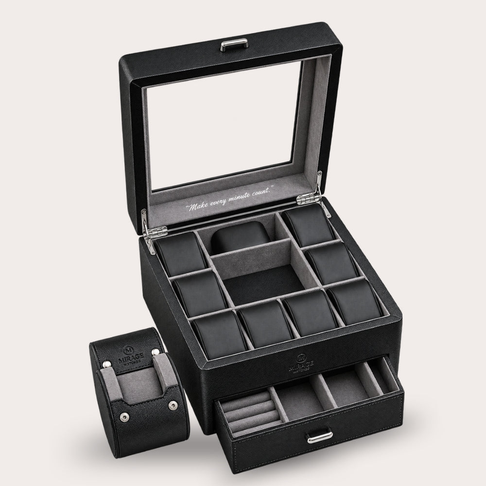 A black leather watch box set shown open on a light beige background, featuring a large main box with a glass lid, multiple watch cushion compartments, and a smaller matching box beside it with its drawer pulled open.