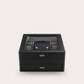 A black leather watch box with a glass top, featuring a central watch slot with a watch inside, two front drawers with silver handles, and a clean light gray background.