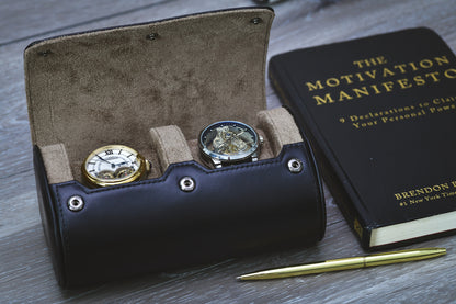 Open Sable Black full-grain cow leather 2 watch roll holding two luxury watches beside The Motivation Manifesto book and a gold pen.