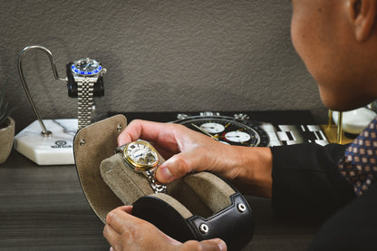 Collector placing a luxury watch into the Sable Black full-grain cow leather 1 watch roll, demonstrating secure storage and everyday protection.
