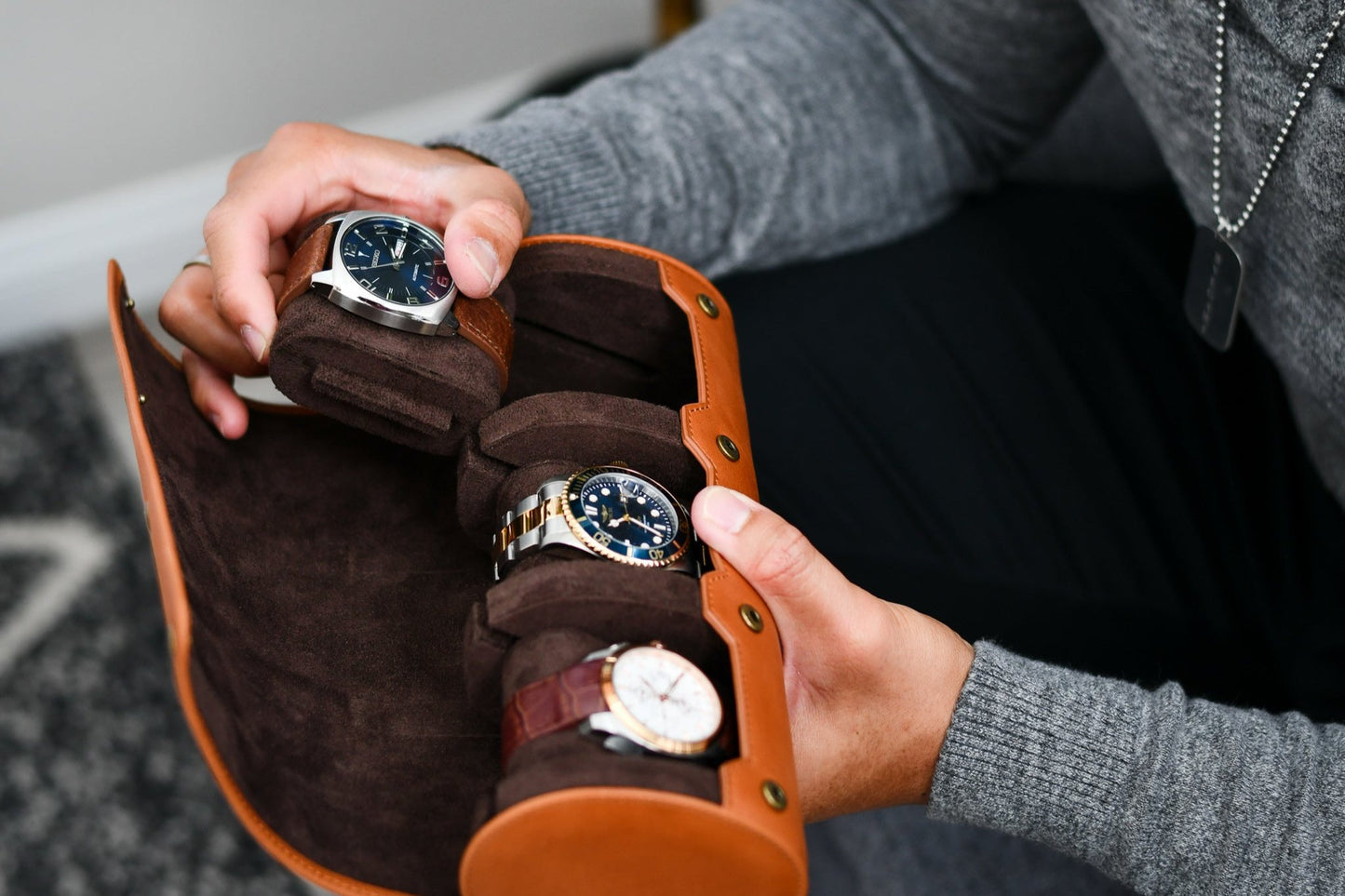 Watch collector organizing luxury watches inside the Mirage Luxury Travel Tawny Brown leather watch roll.