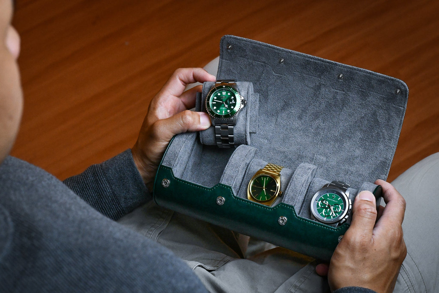 Watch collector placing luxury watches into Royal Green premium vegan leather 3 watch roll with gray suede lining