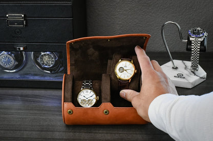 Hand placing a luxury watch into the Mirage Luxury Travel Tawny Brown full-grain cow leather 2 watch roll with signature sliding watch cushions for secure storage.