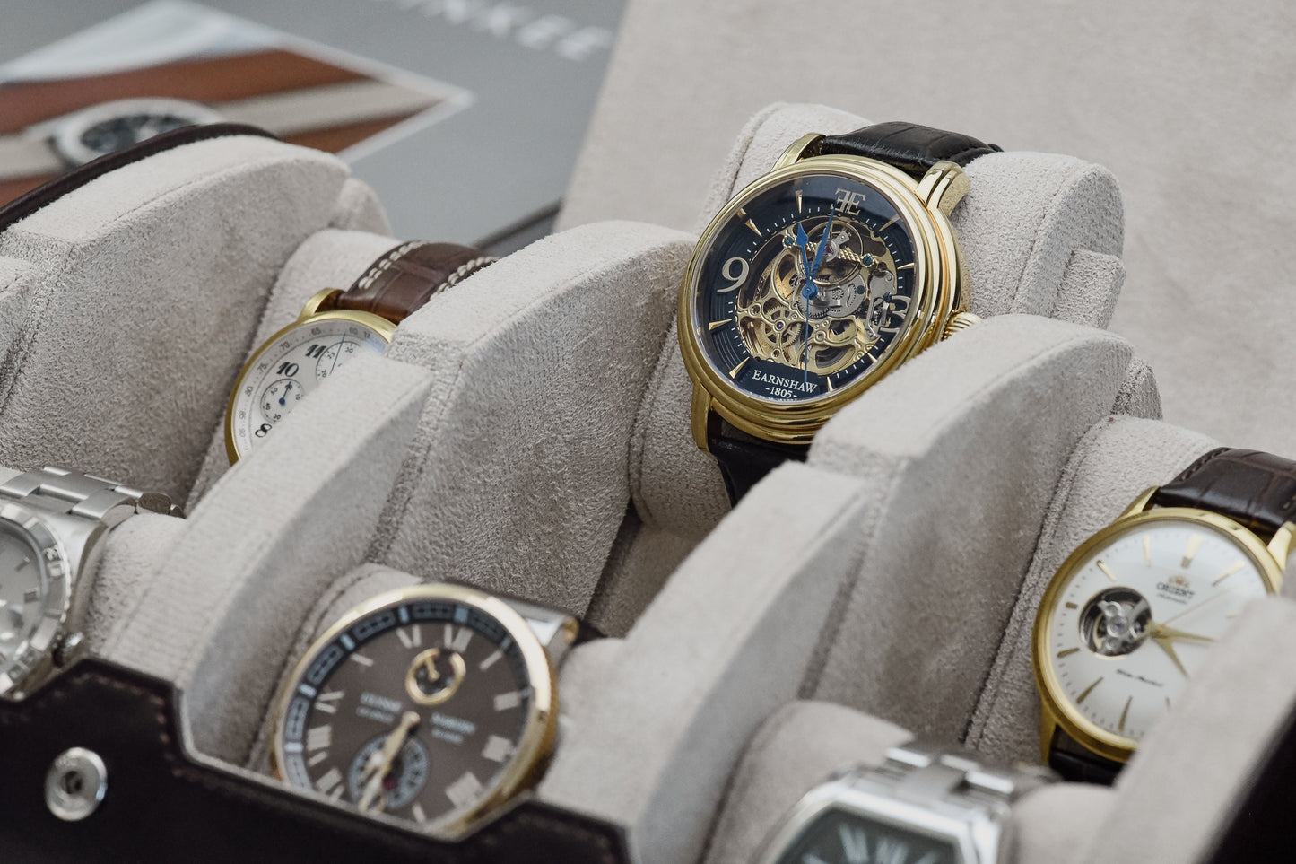 Close-up of luxury watches secured inside Espresso Brown 6 watch travel case with ivory white suede watch cushions