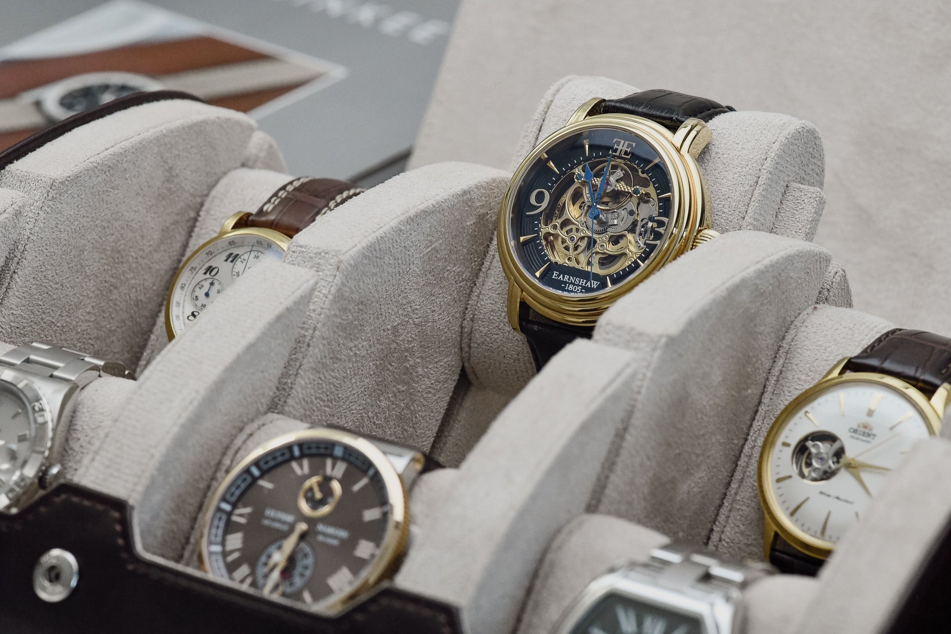Close-up of luxury watches secured inside Espresso Brown 6 watch travel case with ivory white suede watch cushions