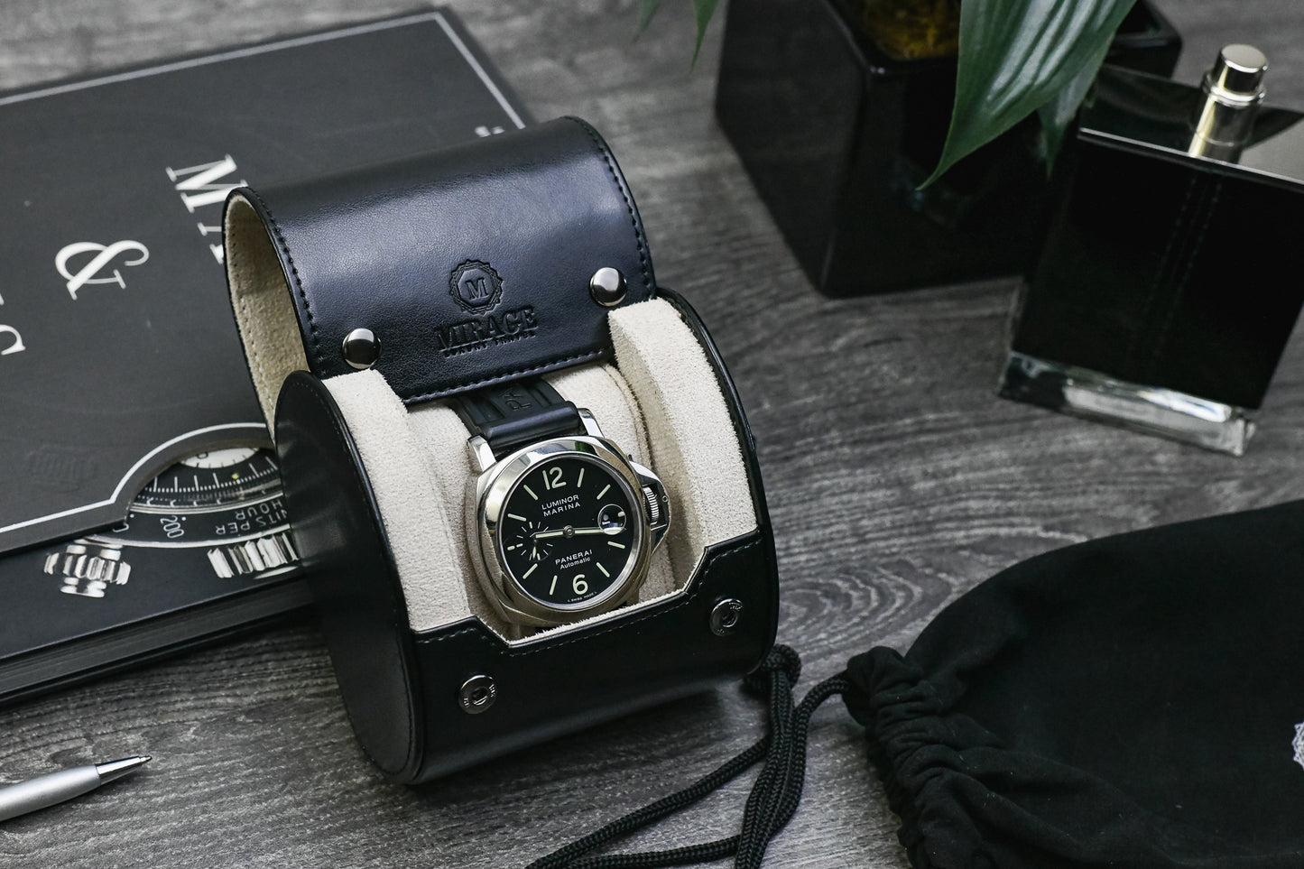 Jade Black vegan leather 1 watch roll with Ivory White interior displayed beside luxury watch accessories on an executive desk.