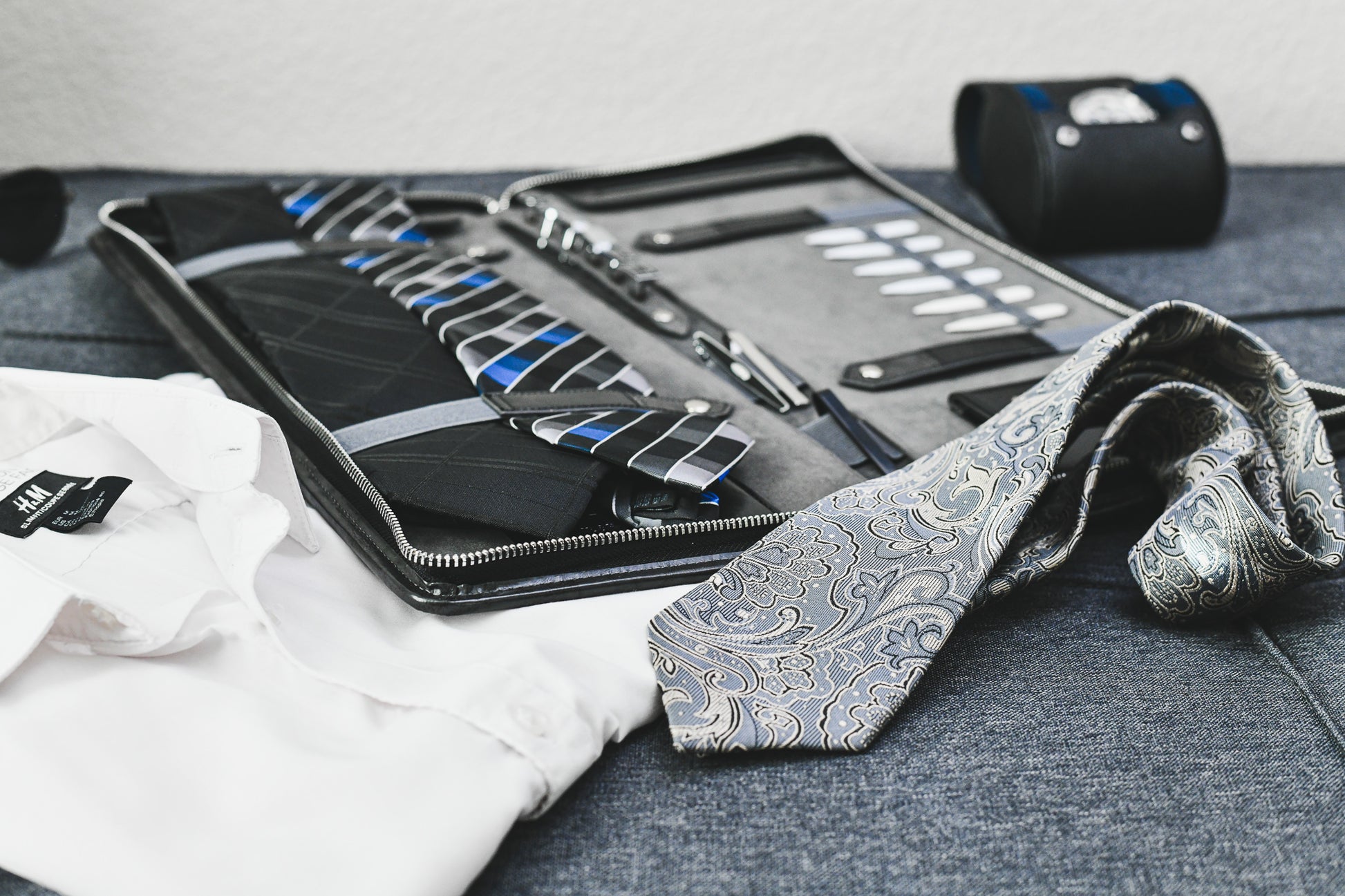 Graphite Black premium vegan leather tie travel case displayed with neckties and business attire, ideal for professionals and frequent travelers.
