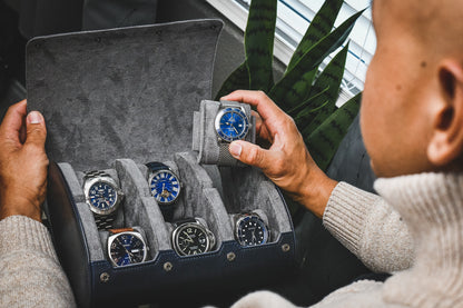Collector organizing luxury watches in a Midnight Blue 6 watch roll with gray suede interior, premium vegan leather travel case for Rolex, Omega, Tudor, Grand Seiko, Breitling, Panerai, Cartier, and Seiko watches.