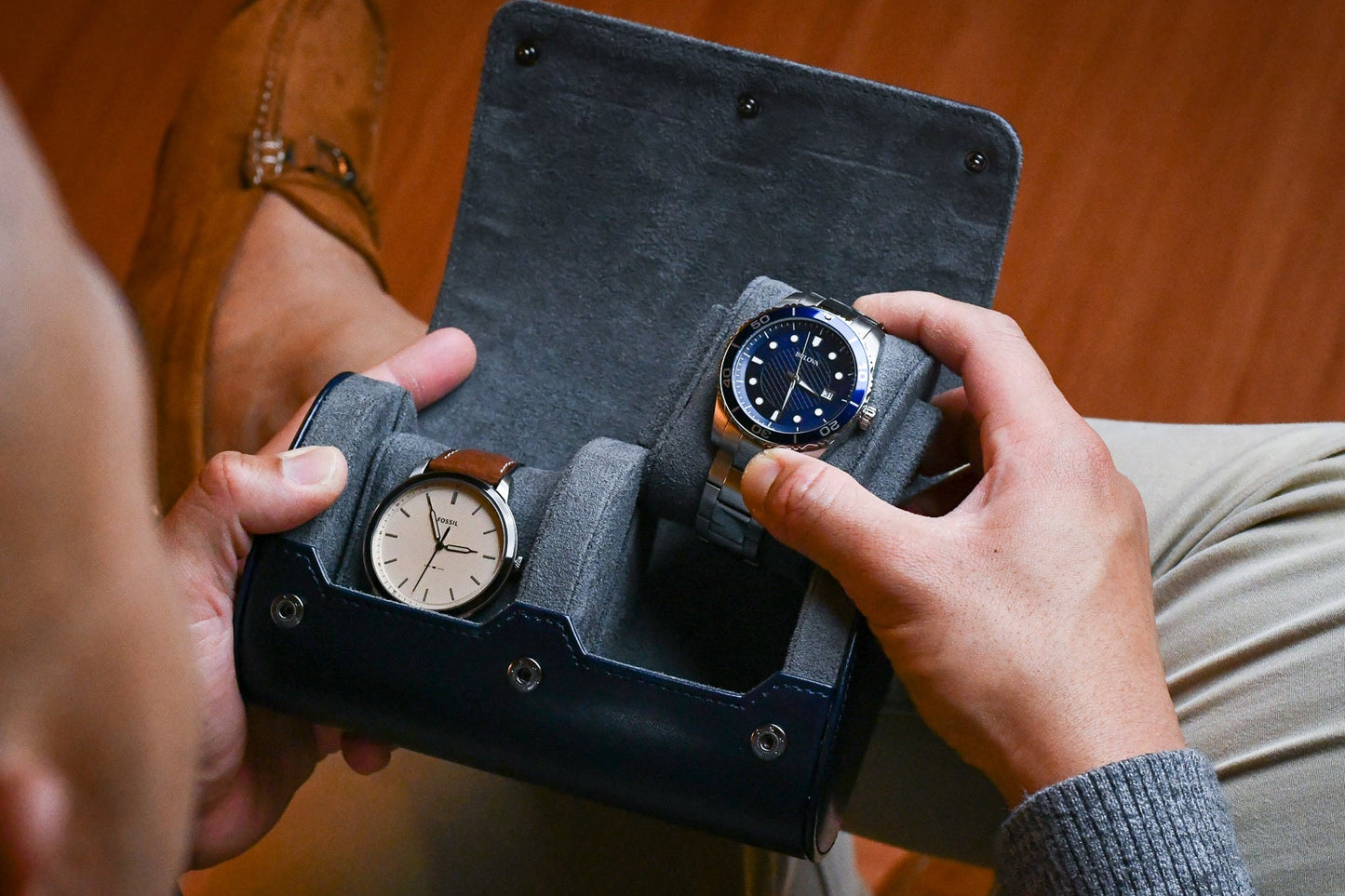 Watch collector placing luxury watches inside the Midnight Blue vegan leather 2 watch organizer with protective suede lining.