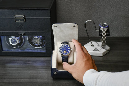 Hand placing a luxury watch into the Midnight Blue vegan leather watch roll with soft blue suede interior.