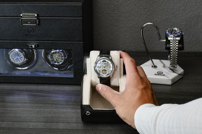 Hand placing a luxury watch into the Mirage Jade Black vegan leather 1 watch roll with signature sliding cushion.
