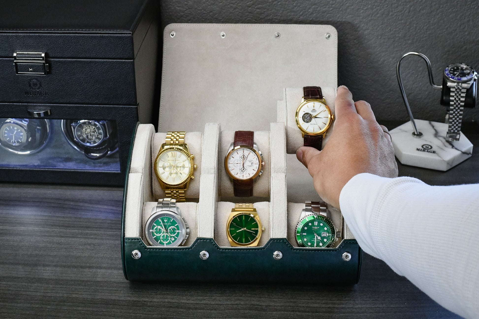 Watch collector organizing luxury watches inside Royal Green 6 watch roll featuring ivory white suede lining and sliding watch cushions