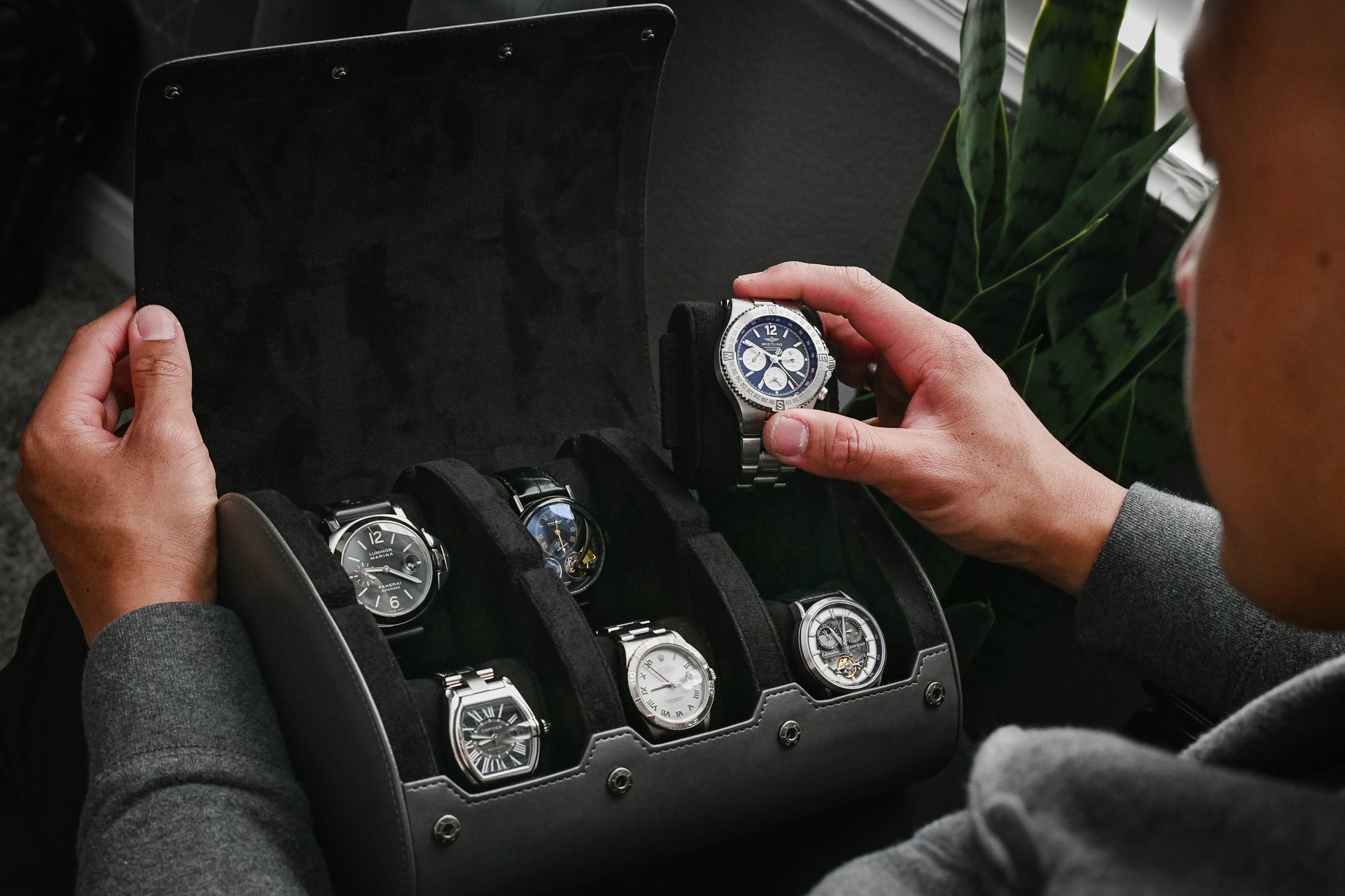 Watch collector organizing luxury watches inside a Slate Gray 6 watch roll with premium suede interior and sliding watch cushions