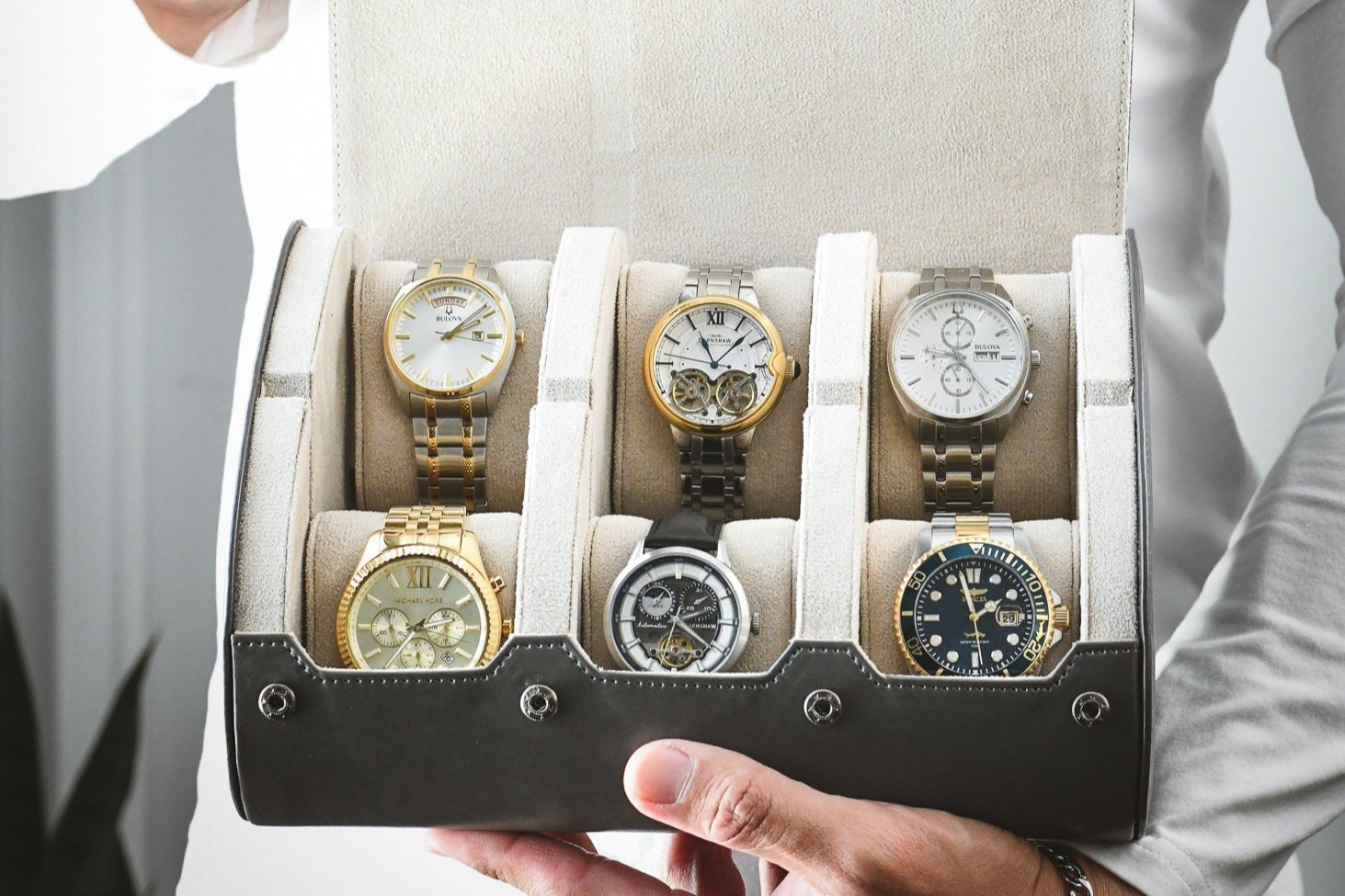 Luxury watches displayed inside Slate Gray premium vegan leather 6 watch roll with ivory white suede interior and sliding watch cushions
