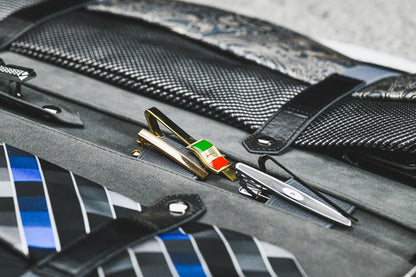 Close-up of dedicated compartments for ties, tie clips, collar stays, and accessories inside the Graphite Black tie travel case.
