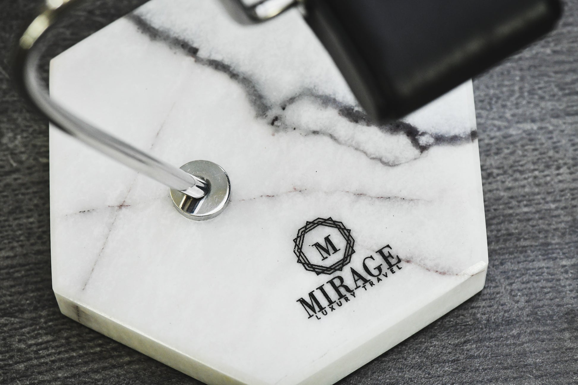 Close-up of the genuine White Lilac Marble base featuring natural stone veining and the Mirage Luxury Travel logo with premium craftsmanship.
